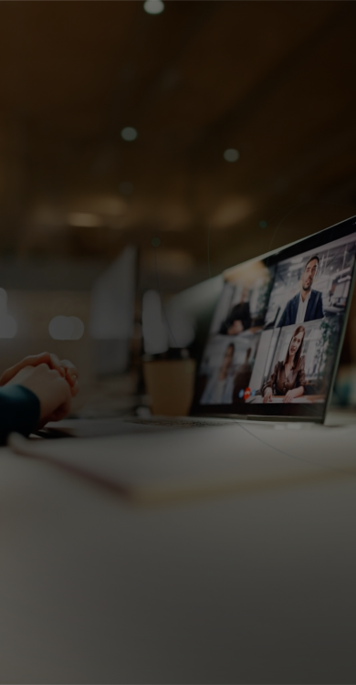 Laptop displaying a virtual video conference with multiple participants in a modern office setting